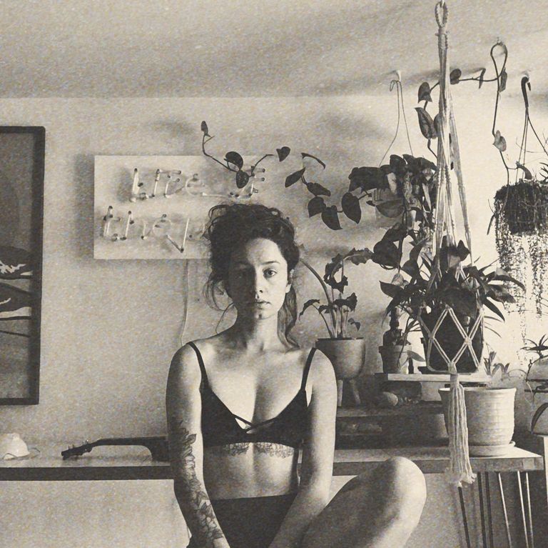 Černovlasá žena Olivia Gatwood s tetováním pod prsy a na ruce sedí v černém spodním prádle ve svém bytě.